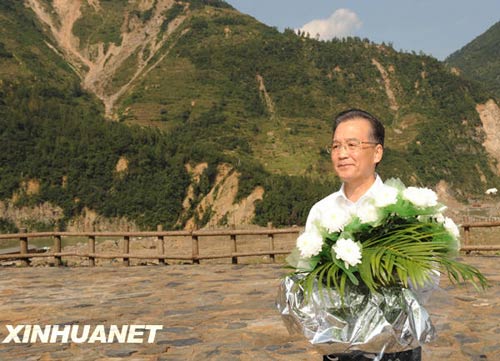 溫家寶總理十分關注災后重建進展情況。在國慶節(jié)和中秋佳節(jié)即將來臨之際，他第8次踏上了一直牽掛的這塊土地。在9月24日至26日的三天時間里，他奔波穿行于地震重災區(qū)的城鄉(xiāng)間，為節(jié)省時間，吃飯盡量安排在火車上；連續(xù)兩個晚上主持召開會議，就災后恢復重建的一系列重大問題進行研究部署。這是9月24日，溫家寶在青川縣紅光鄉(xiāng)東河口村地震遺址祭奠臺獻花。新華社記者黃敬文攝