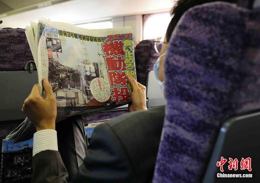 3月17日下午，在一列前往東京的新干線列車上，一名日本人在閱讀關于福島核電站三號機組最新狀況的報道。中新社發(fā) 侯宇 攝