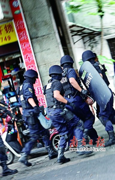 特警將嫌疑人（紅圈內(nèi)）押上警車(chē)。