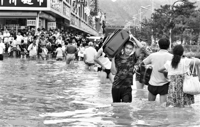 昨日，一名消防戰(zhàn)士在秦皇島市山海關(guān)火車站站前廣場涉水幫助旅客運送行李。 新華社發(fā)